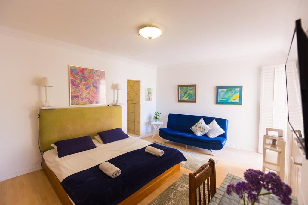 a bedroom with a bed and a blue couch at Ocean Breeze Bloubergstrand in Bloubergstrand