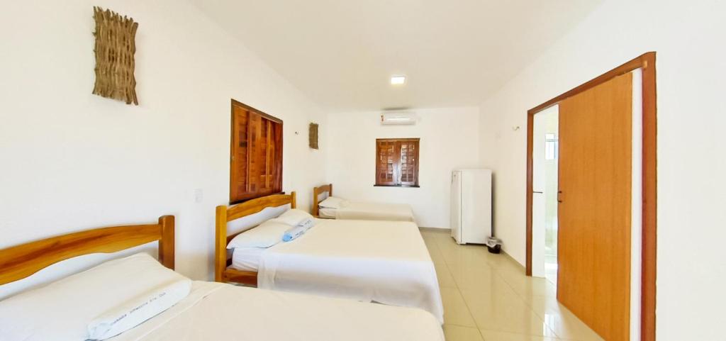 une chambre d'hôtel avec 2 lits et une porte dans l'établissement Amazônia Kite Club, à Luis Correia