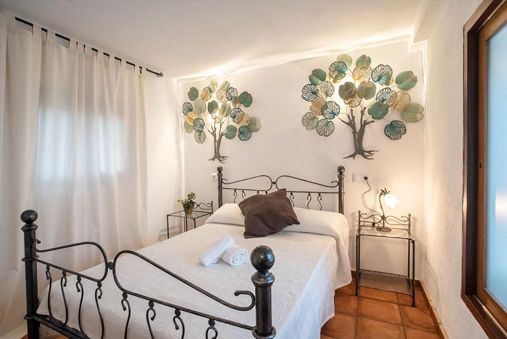 a bedroom with a bed and two flowers on the wall at La Pérgola Habitaciones Rústicas in Es Pujols