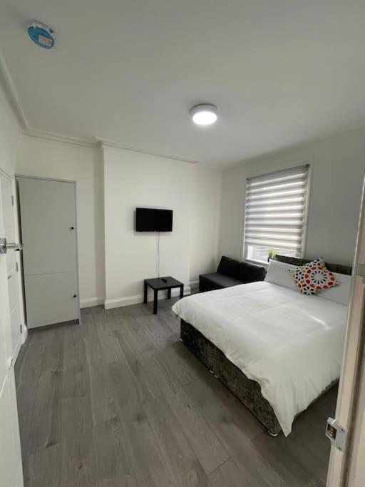 1 dormitorio con 1 cama grande y TV en Luna - Deluxe London Studio Flat en South Norwood