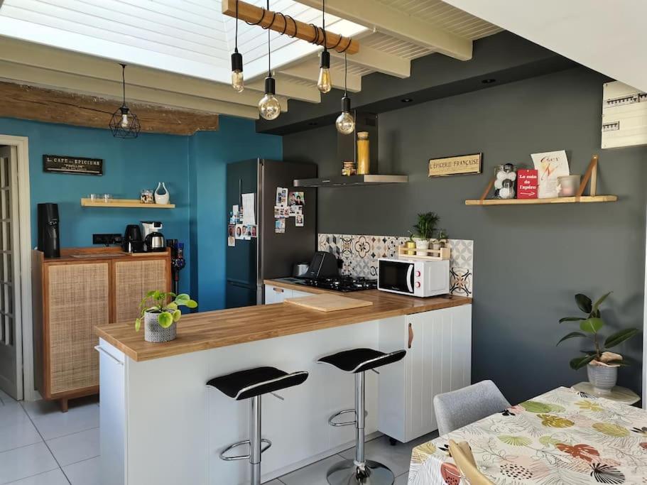 eine Küche mit einer Theke und einigen Hockern in der Unterkunft Maison de centre-ville in Le Mans