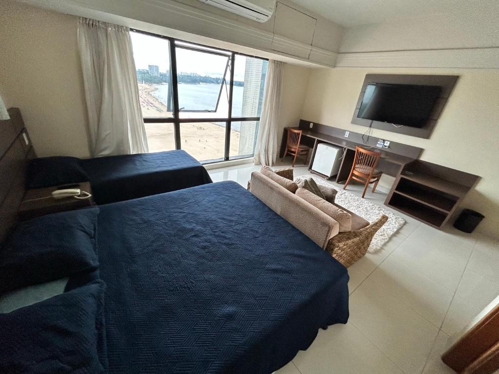 um quarto com uma cama, um sofá e uma televisão em Tropical Executive Flat Vista Incrível para a Orla em Manaus