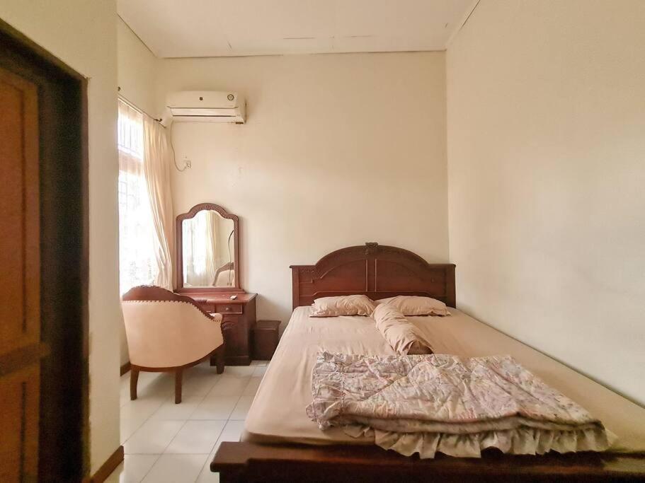 a bedroom with a bed and a chair and a mirror at Homestay Pesona Sintuk Bontang A9 in Bontang