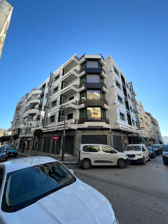 un parking avec des voitures garées devant un grand bâtiment dans l'établissement Crystal boulevard hôtel, à Tanger