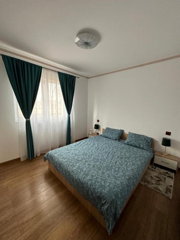 a bedroom with a bed with a blue comforter at Apartament Pruneanu in Câmpia Turzii