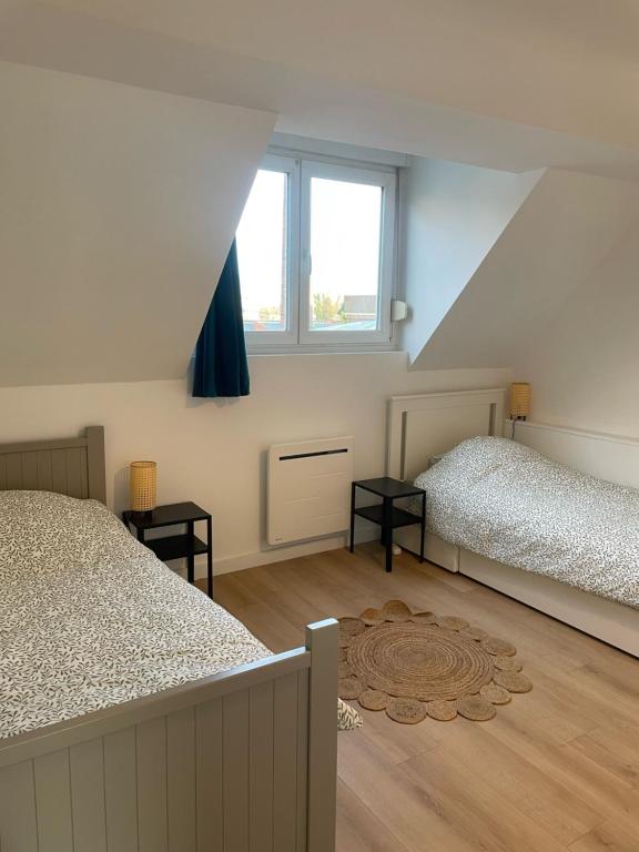 Schlafzimmer im Dachgeschoss mit 2 Betten und einem Fenster in der Unterkunft Maison familiale 3 chambres avec terrasse in Mouvaux