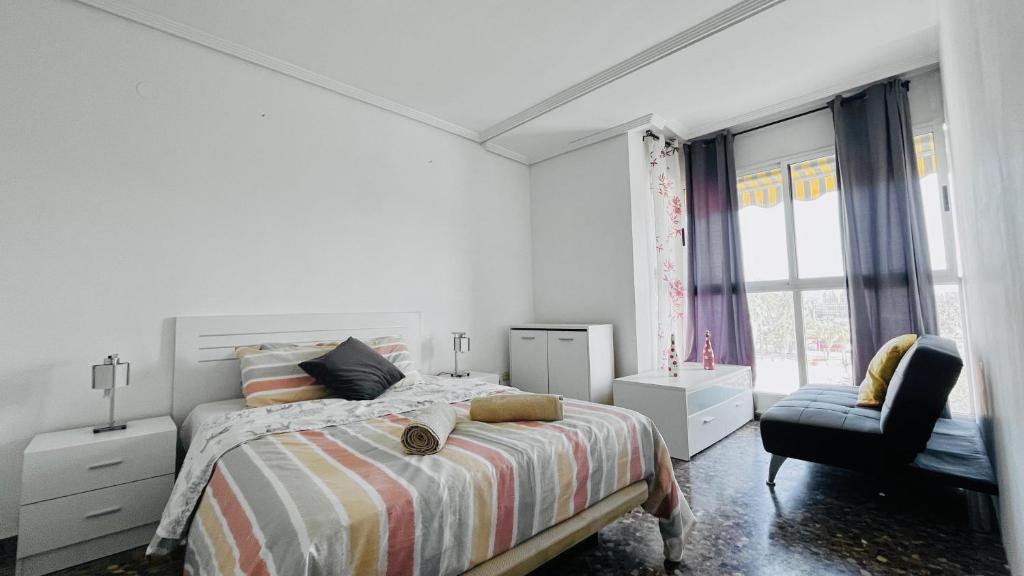 a white bedroom with a bed and a chair at Apartamento Compartido con Vista al Puerto Valencia in Valencia