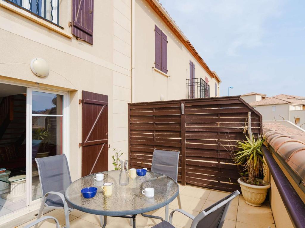un patio avec une table et des chaises sur un balcon dans l'établissement Appartement T3 climatisé à Narbonne-Plage, piscine, proche mer, 4 couchages, animaux acceptés - FR-1-409-2, à Narbonne