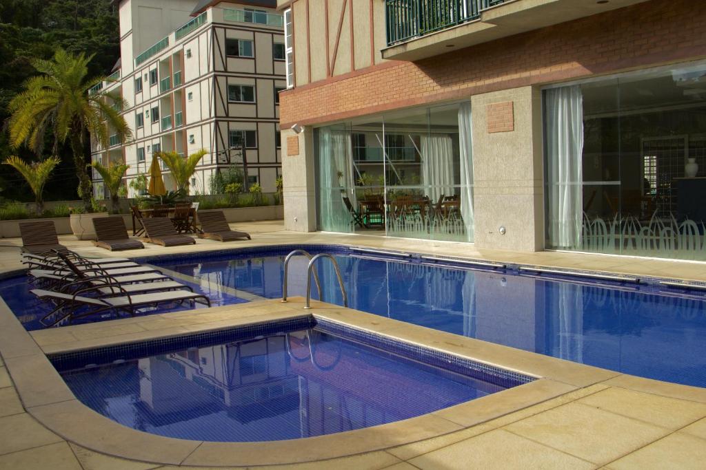 a swimming pool with chairs and a building at Estúdios no Resort Granja Brasil em Itaipava in Petrópolis