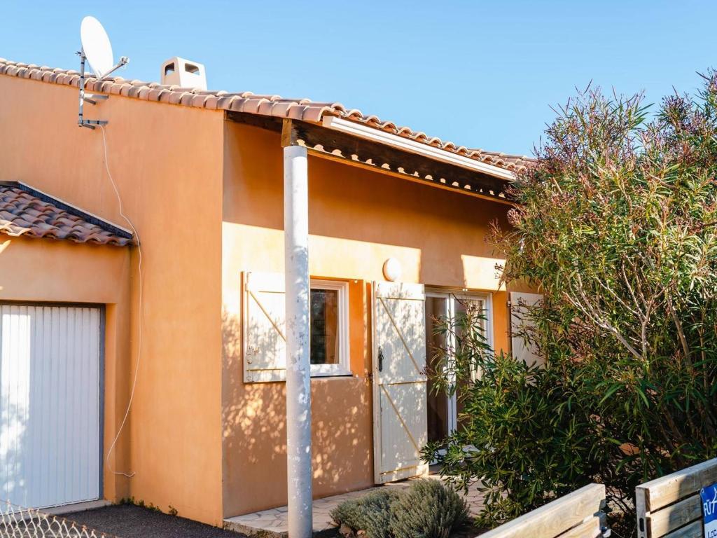 une maison orange avec un portail et un arbre dans l'établissement Villa moderne avec jardin et terrasse, 2 chambres + mezzanine, proche plage - Narbonne-Plage - FR-1-409-102, à Narbonne-Plage