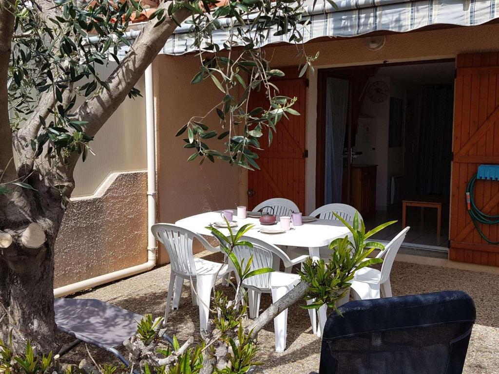 une table blanche et des chaises sur une terrasse dans l'établissement Pavillon cosy avec terrasse, 5 couchages, proche plage et nature, animaux bienvenus - FR-1-409-95, à Narbonne-Plage