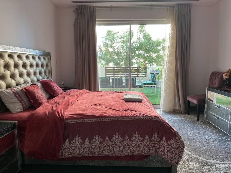 a bedroom with a bed with a red comforter and a window at Lyoan home in Ḩayl Āl ‘Umayr