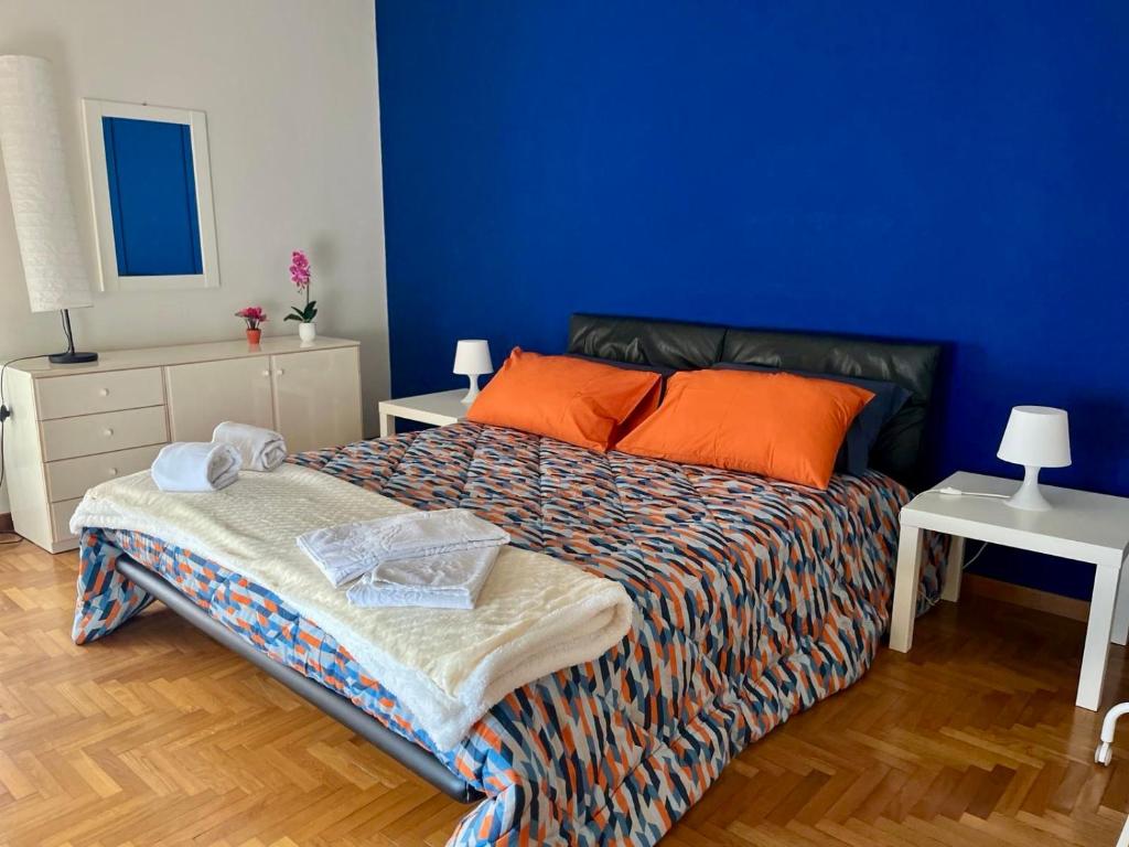 1 dormitorio con 1 cama con almohadas de color naranja y pared azul en Benvenuti a Casa Sicilian Apartment Palermo, en Termini Imerese