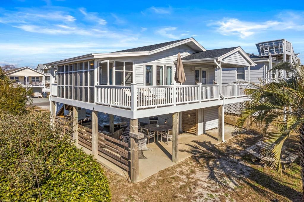 a large house with a porch and a deck at Dunebug Cottage 319 Sandpiper Lane home in Holden Beach