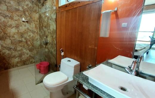 a bathroom with a white toilet and a sink at zoz Mg in Old Goa