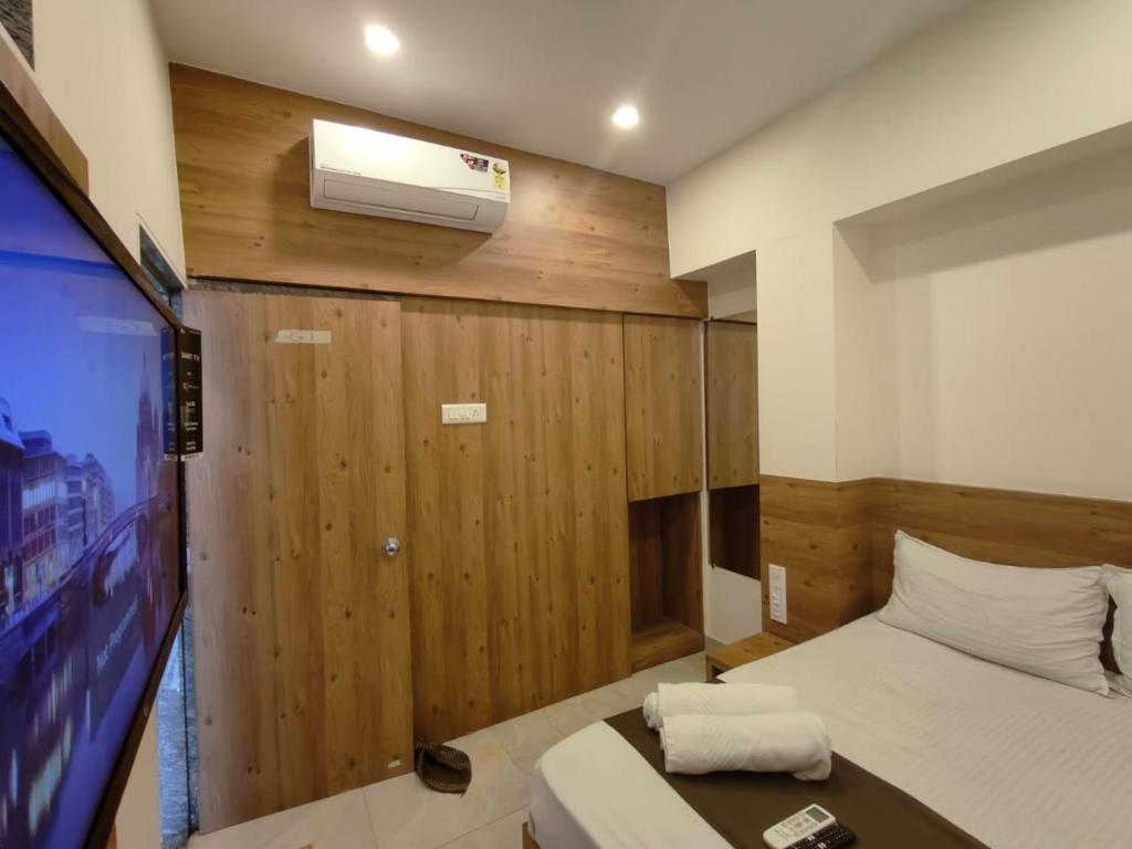 a room with a bed and a tv at Hotel Apple Inn - Santacruz in Mumbai