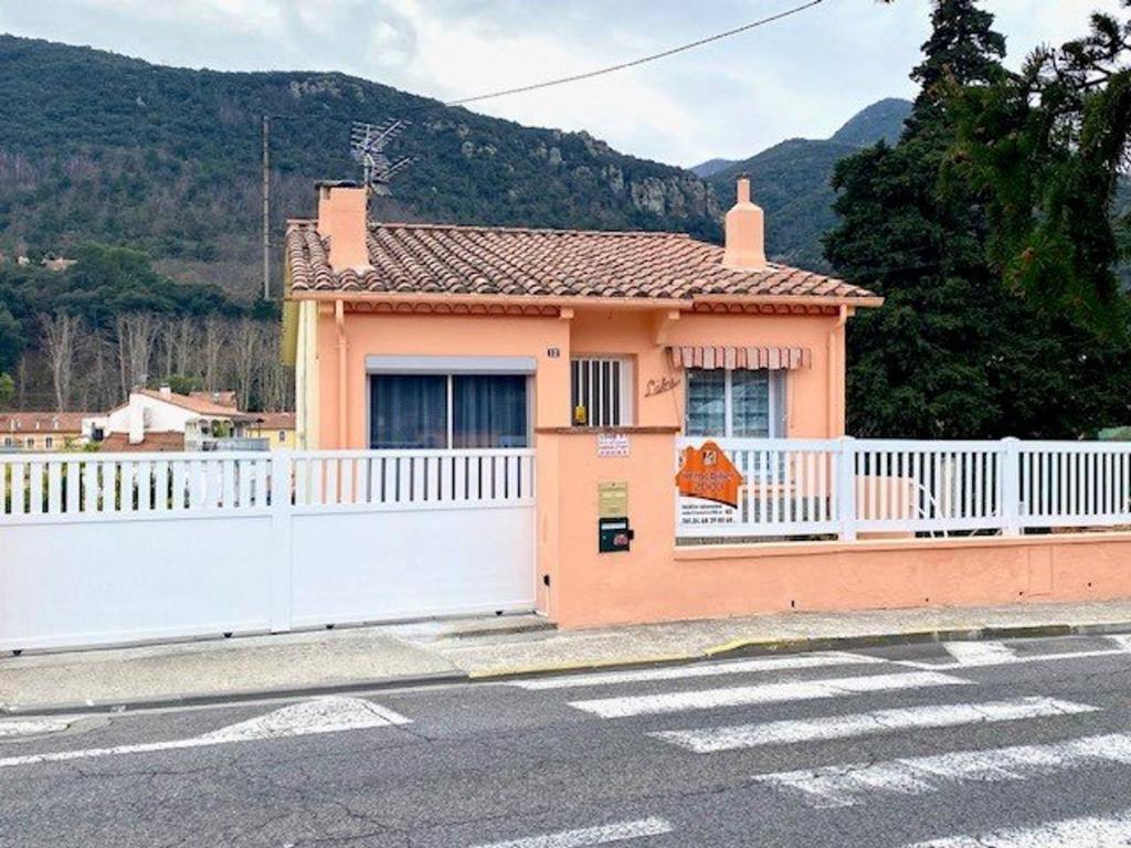 une petite maison orange avec une clôture blanche dans l'établissement Spacieux F2 ensoleillé de 62m², climatisé, balcon, parking, proche cures et centre, animaux acceptés - FR-1-703-121, à Amélie-les-Bains-Palalda