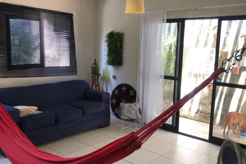 een woonkamer met een blauwe bank en een hangmat bij Casa com área externa in Natal