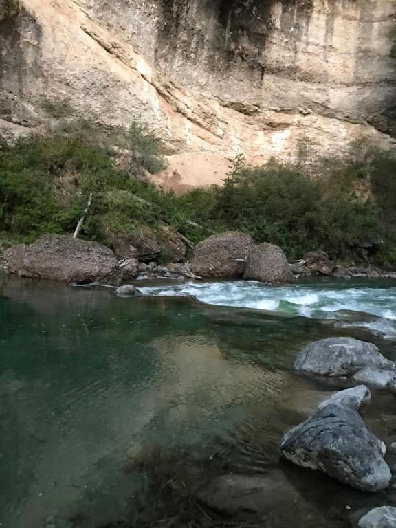 un arroyo de agua con rocas delante de una montaña en Alquileres Mallin en Los Repollos