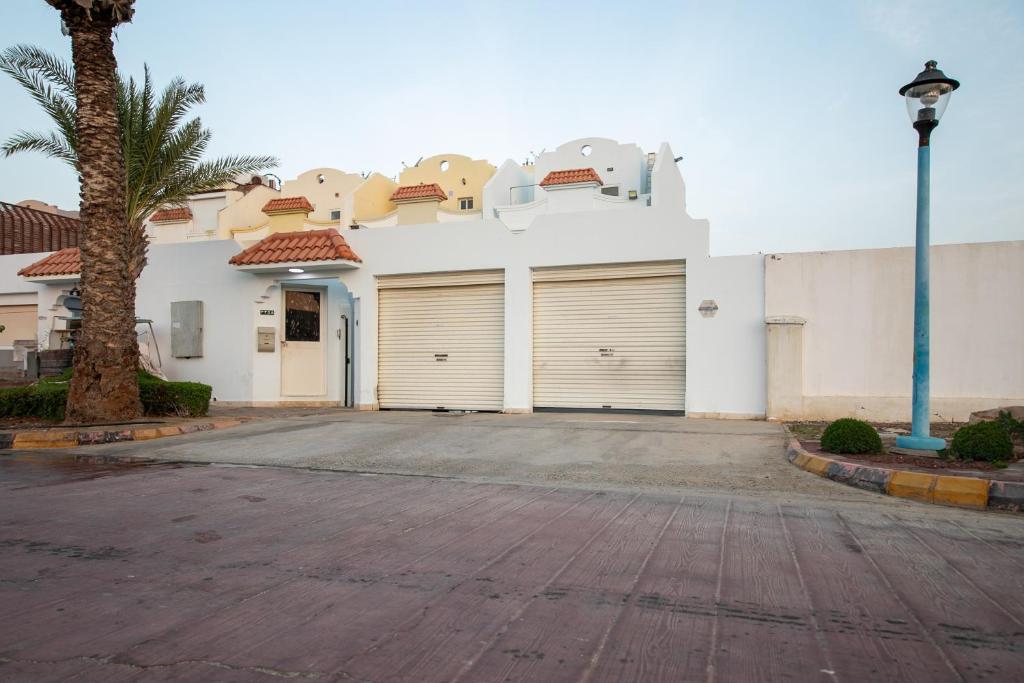 a white building with two garage doors and a palm tree at Blue Star Villa in Durat Alarous