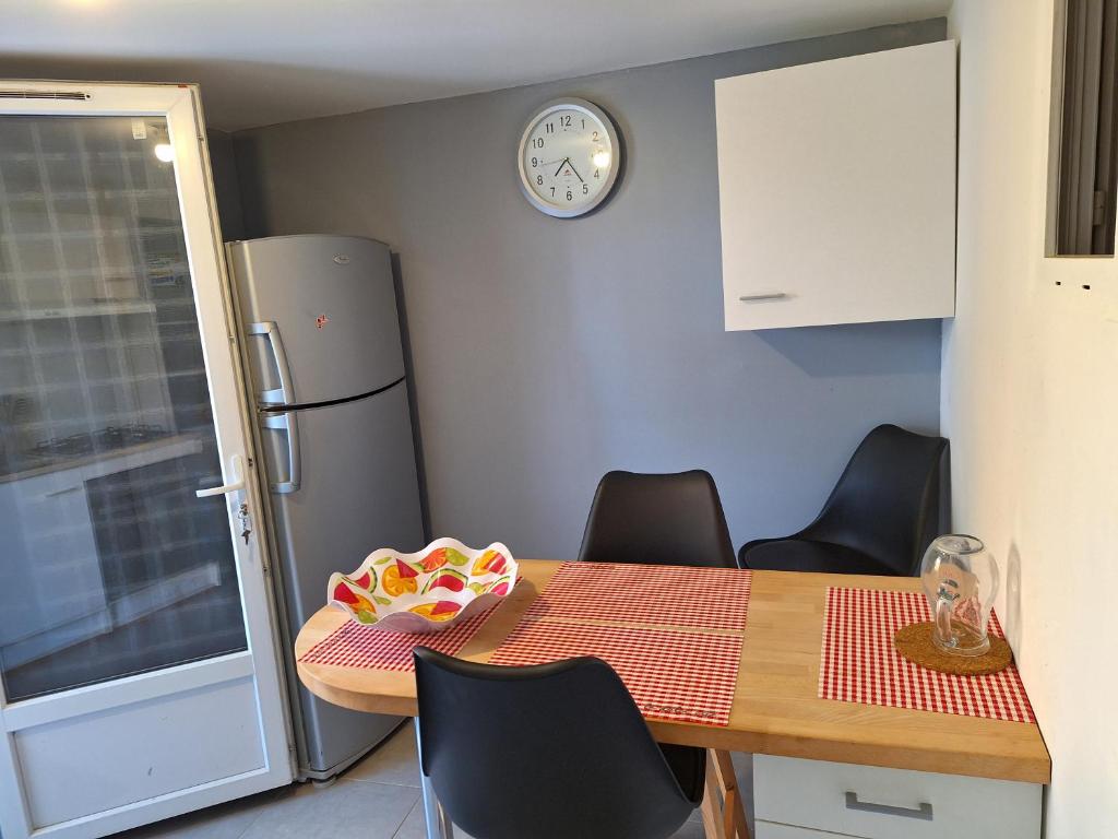 een keuken met een tafel met stoelen en een koelkast bij Agréable Studio tout équipé in Montsoué