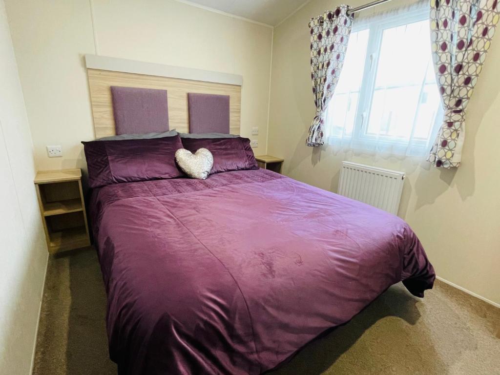 a bed with a purple comforter in a bedroom at Water Sky Getaways 3-bedroom caravans at Durdle Door in Wareham