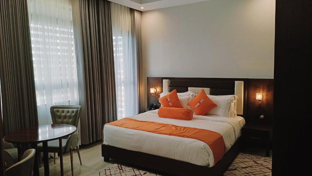 a hotel room with a bed with orange pillows and a table at Lemaiyan Suites in Naivasha