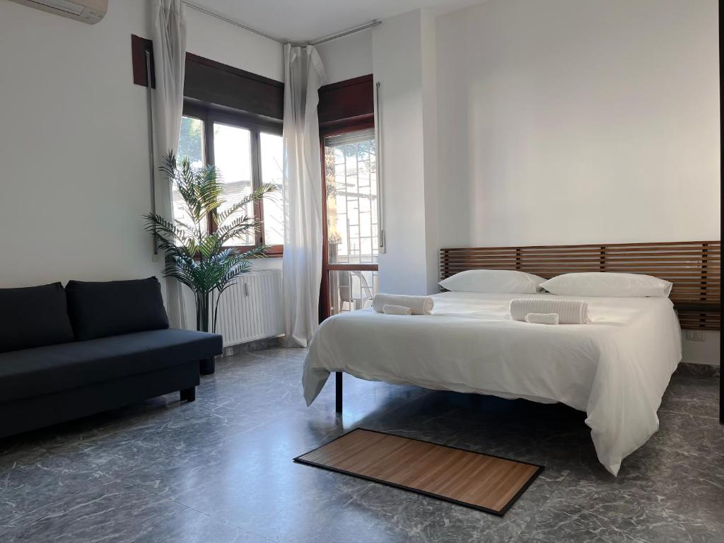 ein Schlafzimmer mit einem großen weißen Bett und einem Sofa in der Unterkunft Pascià Rooms in Rom