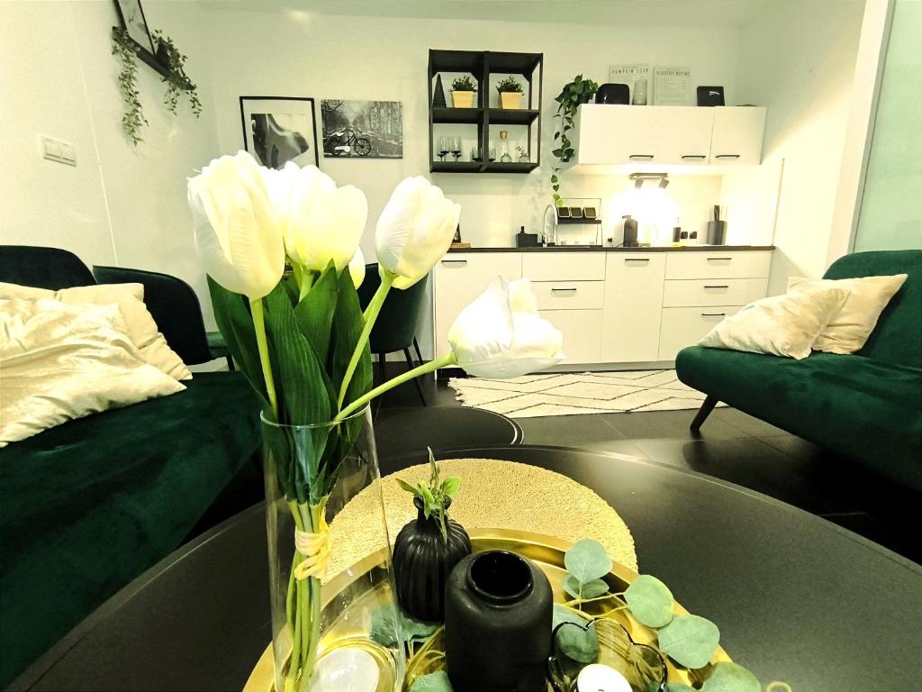 - un vase avec des fleurs blanches sur une table dans le salon dans l'établissement Park Bôrik 4YOU & Free Parking, à Žilina