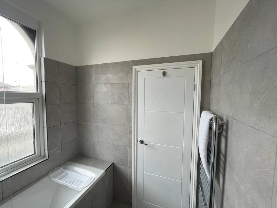 La salle de bains est pourvue d'une douche, de toilettes et d'une fenêtre. dans l'établissement Pearl- Deluxe London Studio Flat, à South Norwood