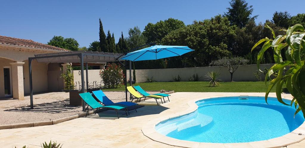 a swimming pool with two chairs and an umbrella at Les Dentelles du Ventoux - Gîte avec Piscine in Aubignan