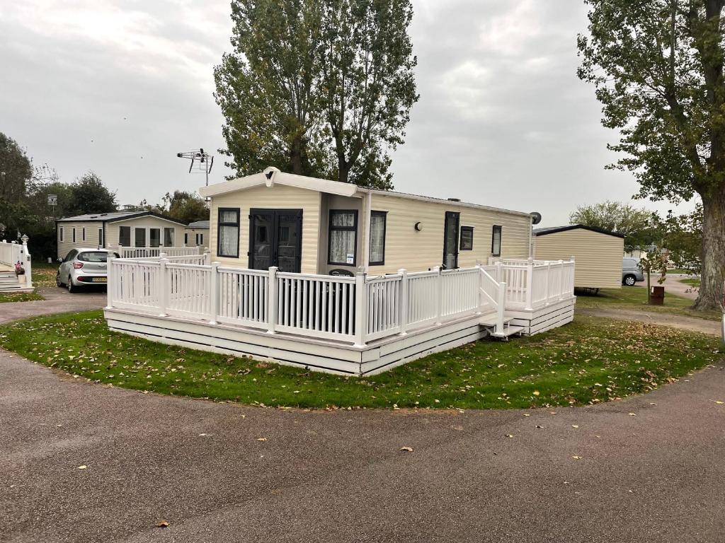 a white house with a porch on the grass at Highfield Grange Caravan Park (Parkdean) in Little Clacton