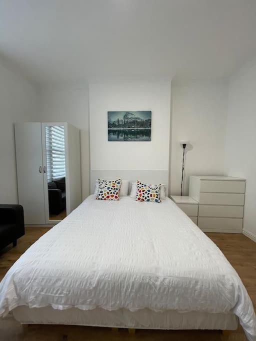 ein weißes Schlafzimmer mit einem großen weißen Bett mit Kissen in der Unterkunft Garnet - Deluxe London Studio in South Norwood