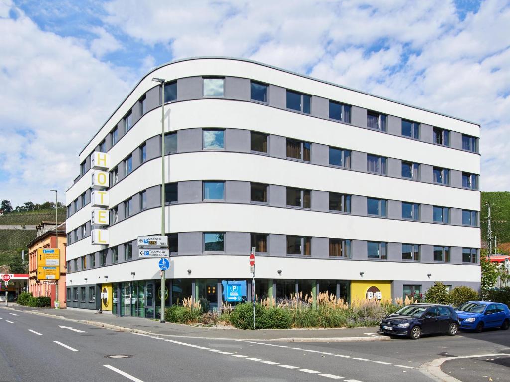 un edificio blanco con coches estacionados frente a él en B&B Hotel Würzburg, en Würzburg