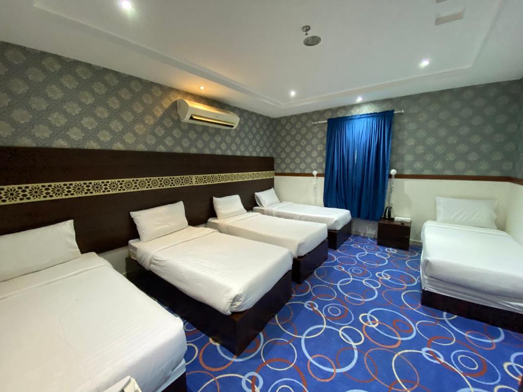 a room with four beds and a blue carpet at Negmat Sedqy Makkah in Makkah