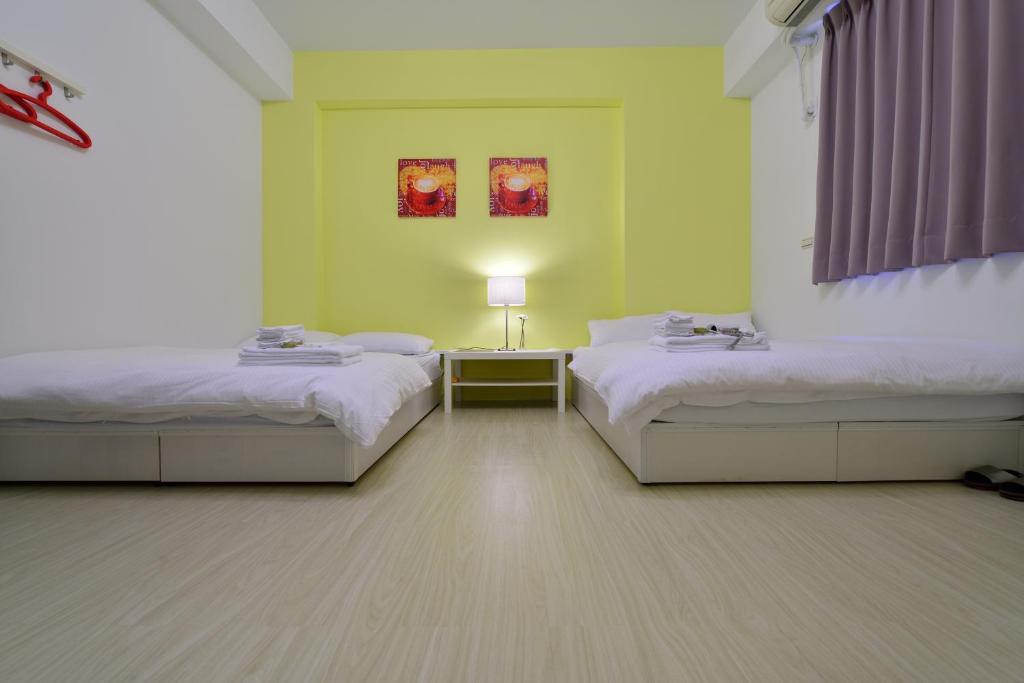 a room with two beds and a table with a lamp at STSP Guest House in Xinshi