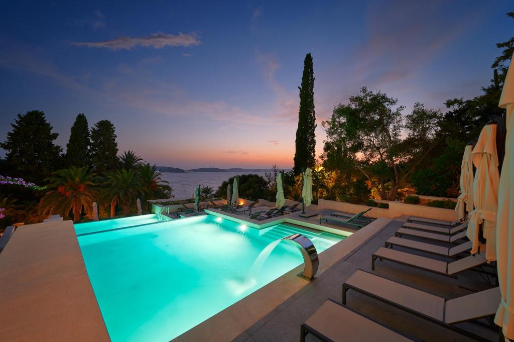 a swimming pool with chaise lounge chairs next to a house at Hotel Moeesy, Blue & Green Oasis in Hvar