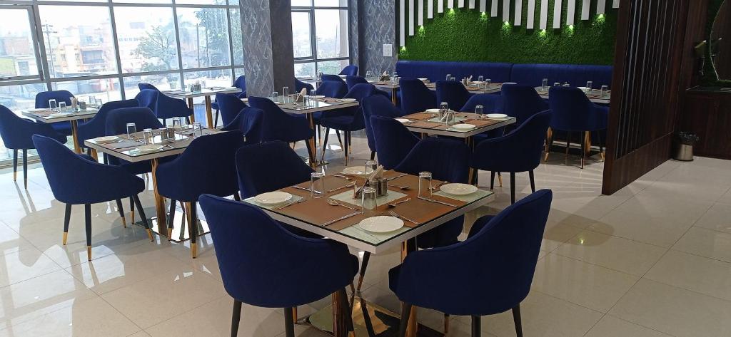een eetkamer met tafels en blauwe stoelen bij Hotel JVW Arena in Motīhāri
