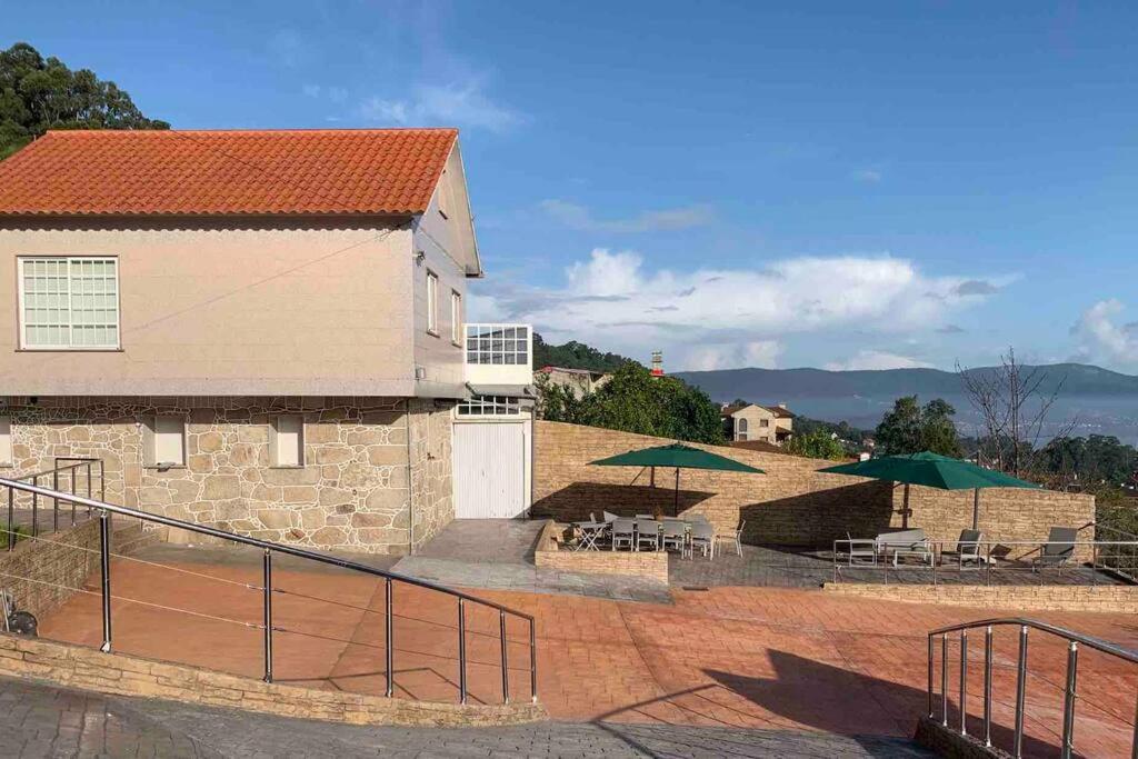 un bâtiment avec des parasols verts, des tables et des chaises dans l'établissement Acogedora casa cerca de Marín, à Pontevedra