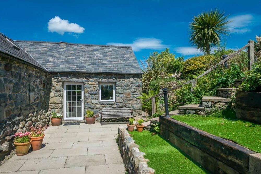 a stone cottage with a bench and a garden at Ty-Gwair-Byrdir in Dyffryn