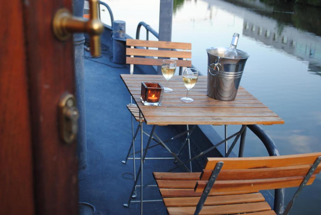 een houten tafel met twee glazen wijn erop bij Boat & Breakfast Bellevue in Gent