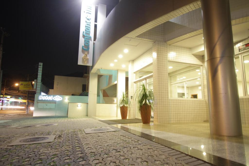 Hotel Confiance Centro Cívico في كوريتيبا: مبنى في الليل مع نباتات الفخار في الخارج