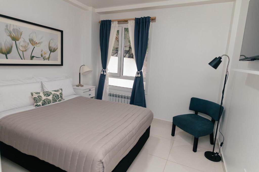 a bedroom with a bed and a chair and a window at Departamentos Patagonia in Ushuaia