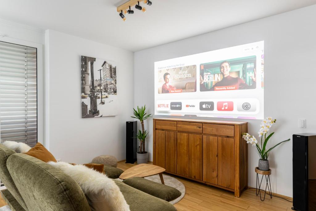 sala de estar con sofá y TV de pantalla plana en EDLER WOHNRAUM Panoramablick 3 Schlafzimmer mit Boxspringbetten Klimaanlagen Kaffeevollautomat & Tiefgarage mit E-Ladestation, en Graz