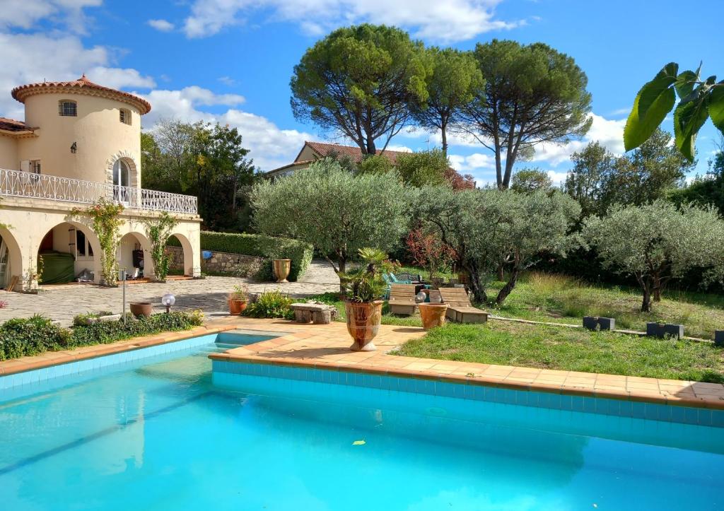 a pool in front of a house with trees at le relais fleuri in Alès