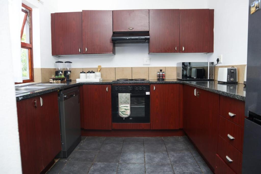a kitchen with wooden cabinets and a stove top oven at Spacious and luxury 3 bedroom apartment in Midrand