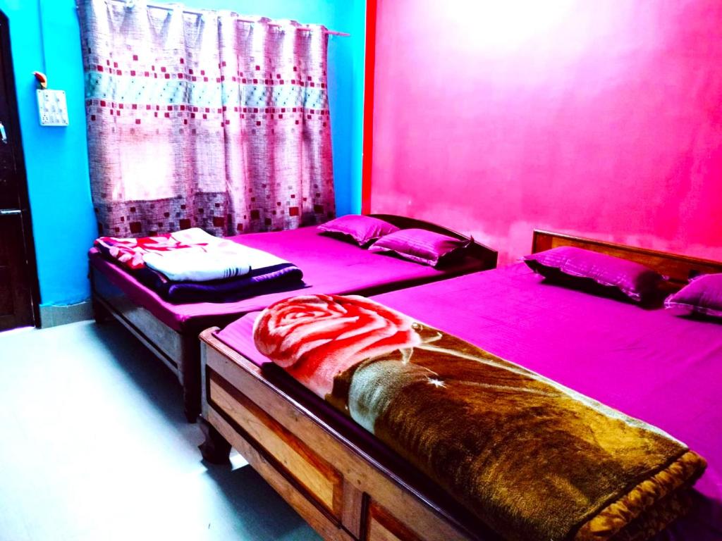two twin beds in a room with pink at Hotel Green Gold Resort Lataguri in Lataguri