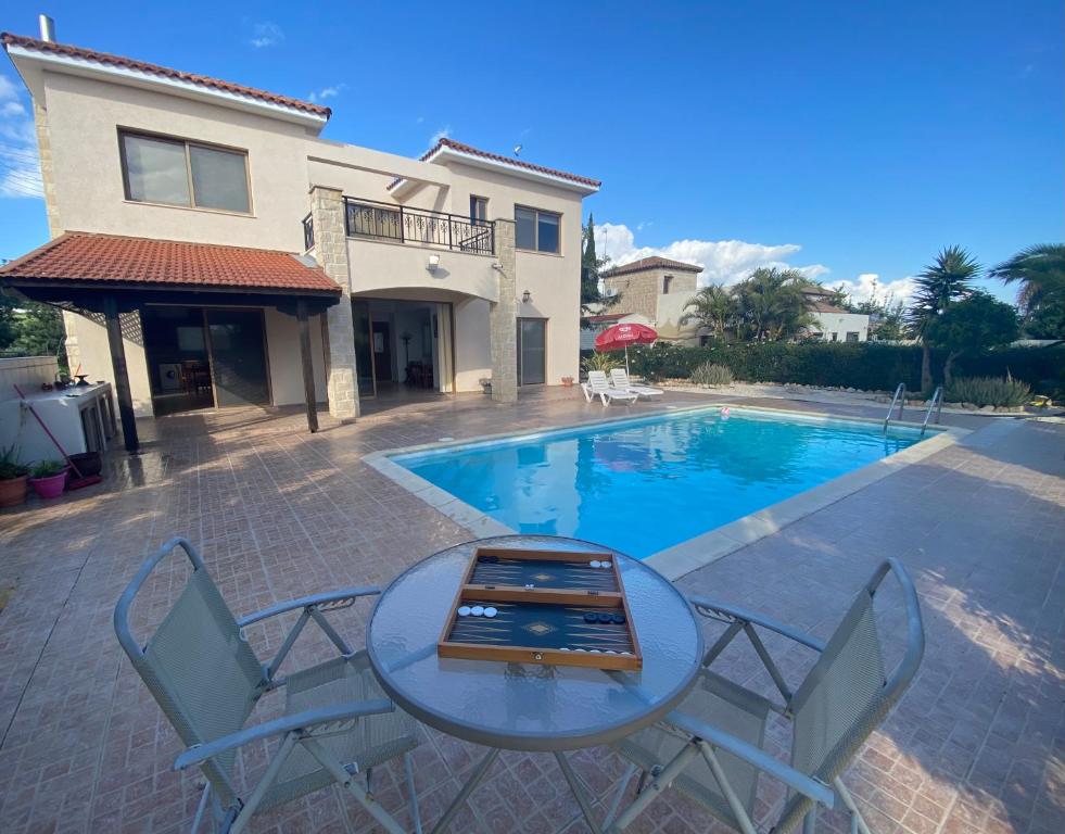 - une table et des chaises à côté de la piscine dans l'établissement Villa Ariadni, à Pissoúri