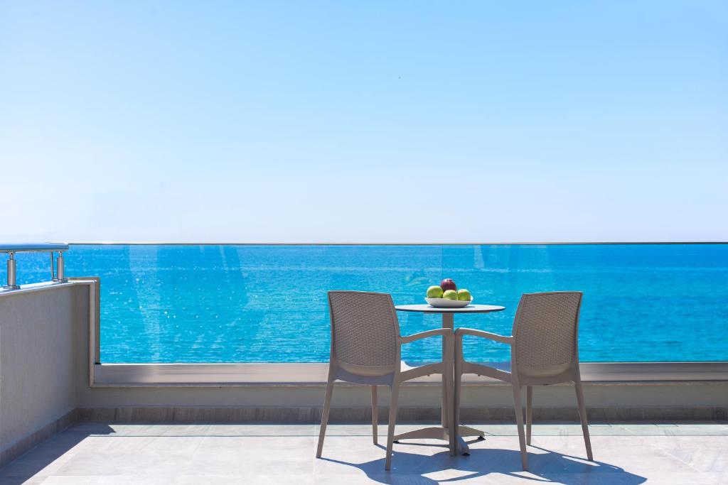 Aegean Infinity Deluxe في يميناريا: طاولة وكراسي في غرفة مطلة على المحيط