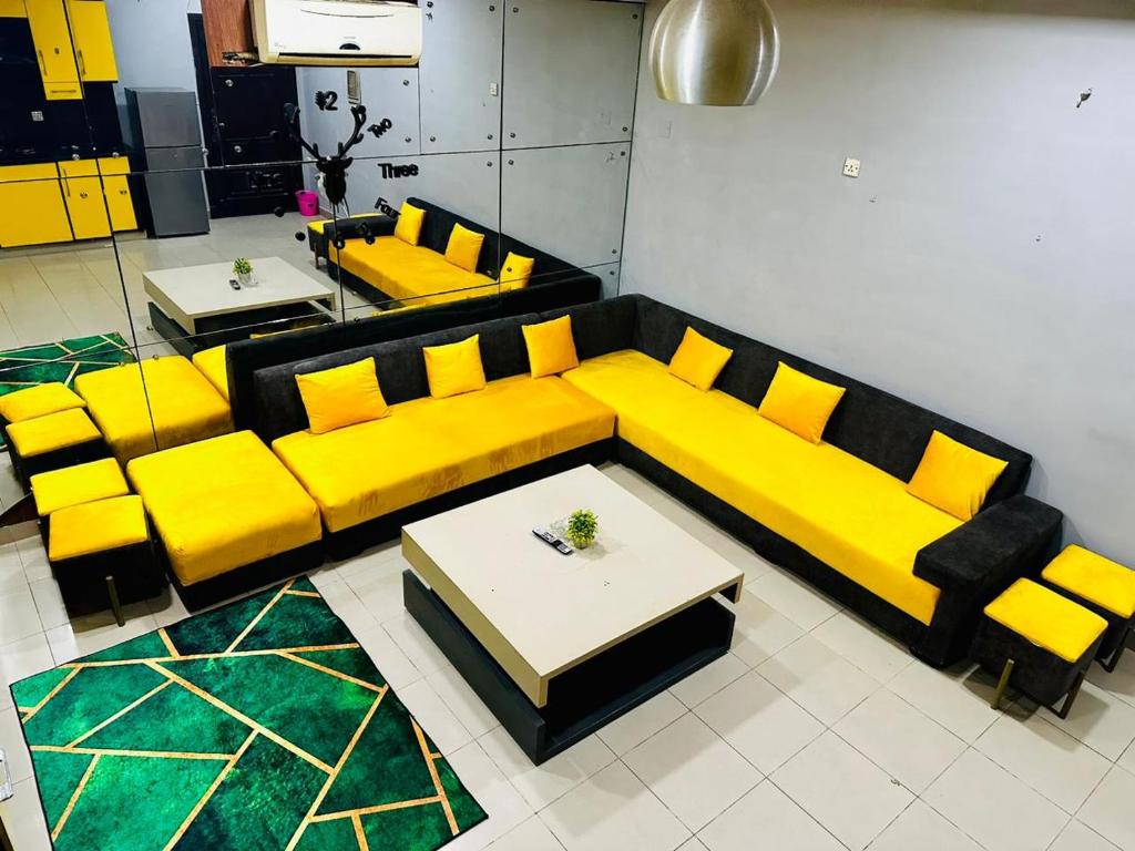 a living room with a yellow couch and a table at Den in Rawalpindi